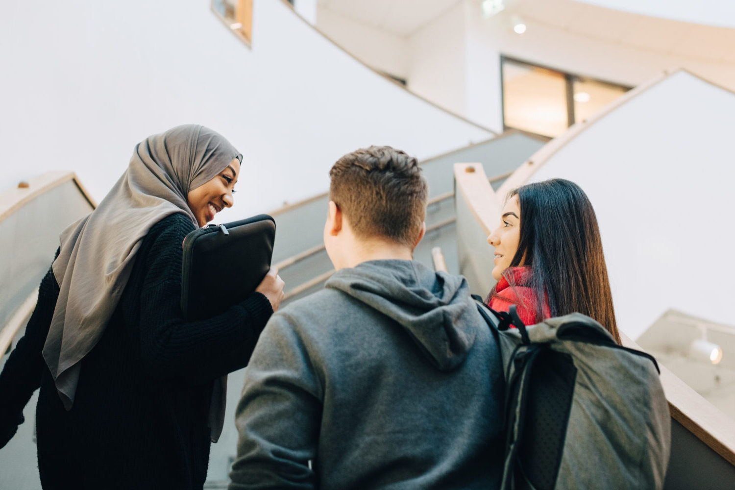 Rear view of teenage students walking up on staircase at university
